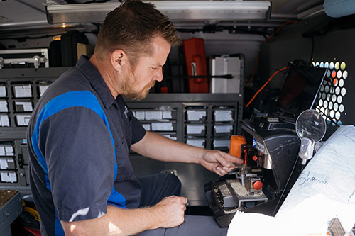 Noble locksmith cutting a new car key inside his locksmith van